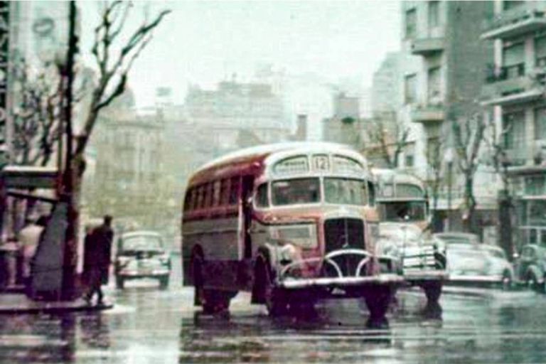 Dos colectivos de la línea 12 circulan por la Avenida Santa Fe en el cruce por Pueyrredón un día lluvioso del año 1960