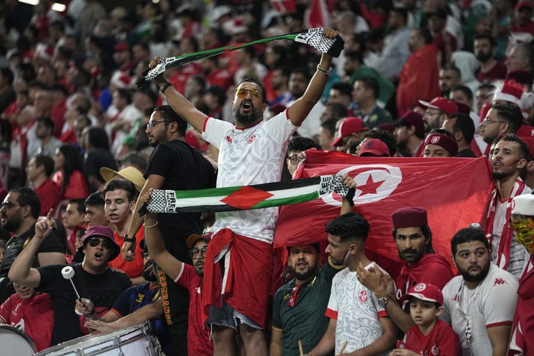 Torcedores seguram bandeiras palestinas enquanto torcem pela seleção da Tunísia durante uma partida do Grupo D da Copa do Mundo entre Dinamarca e Tunísia, no estádio Education City em Rayyan, Catar, em 22 de novembro de 2022. (AP Photo/Ariel Schalit)