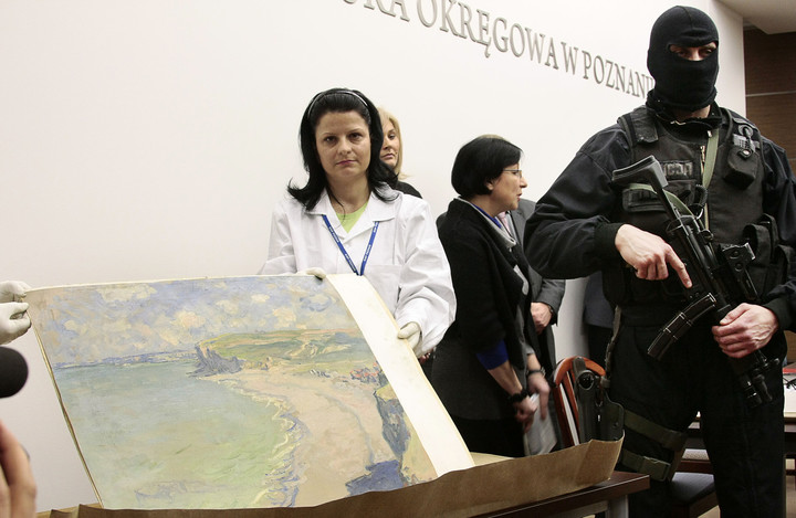 Funcionarios del Museo Nacional de Arte de Poznan sostienen una pintura del impresionista francés Claude Monet, robada hace en el 2000 y recuperada una década después.